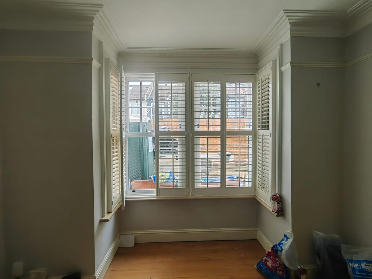 Timber bay windows dressed with white plantation shutters in a period living room