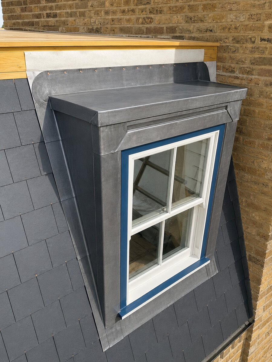 Blue-framed timber sash window in a lead-clad dormer on a slate roof