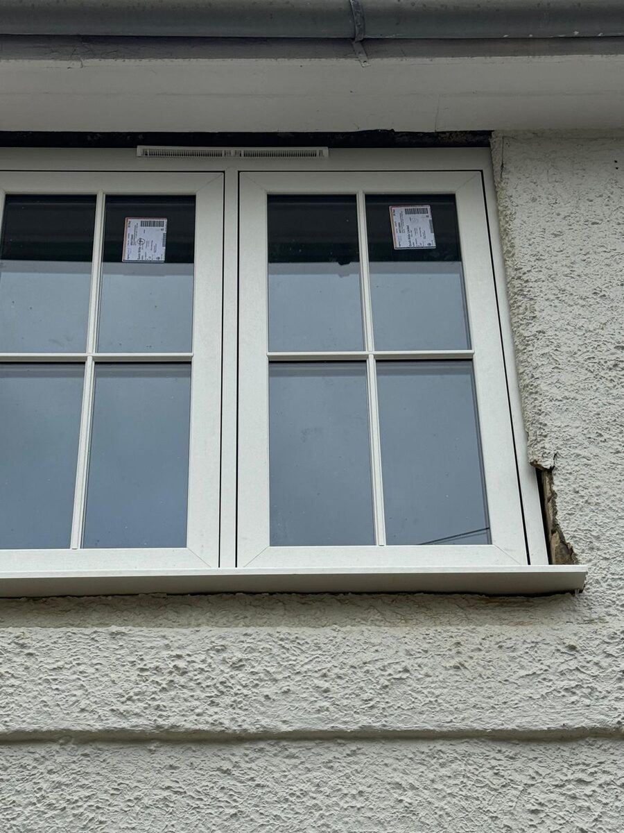 Newly installed white timber casement windows with glazing bars on a rendered cottage