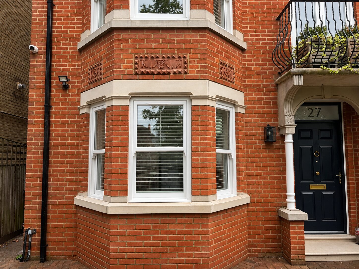 New white timber sash windows in a red-brick Victorian bay with stone detailing