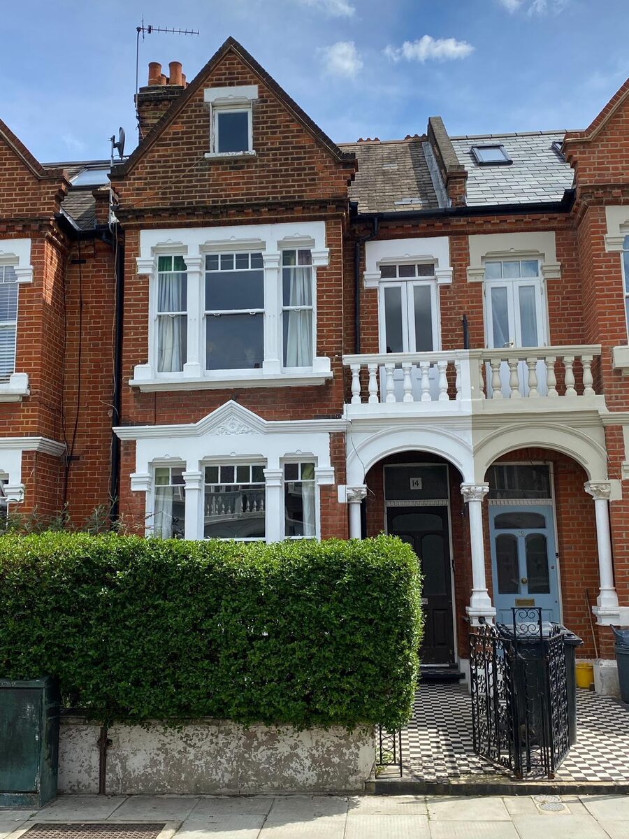 Red-brick Victorian terrace with restored white timber sash windows and balcony