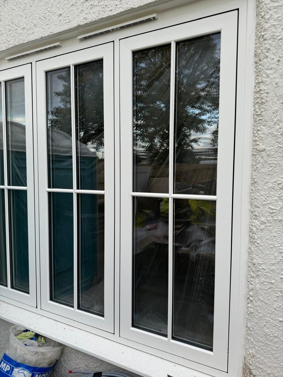 White timber casement windows with Georgian glazing bars on a rendered house